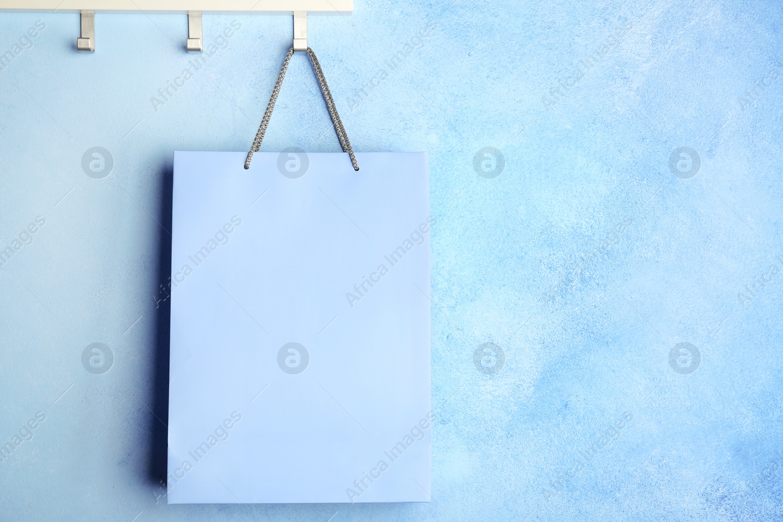 Photo of Rack with paper shopping bag on color wall. Mockup for design