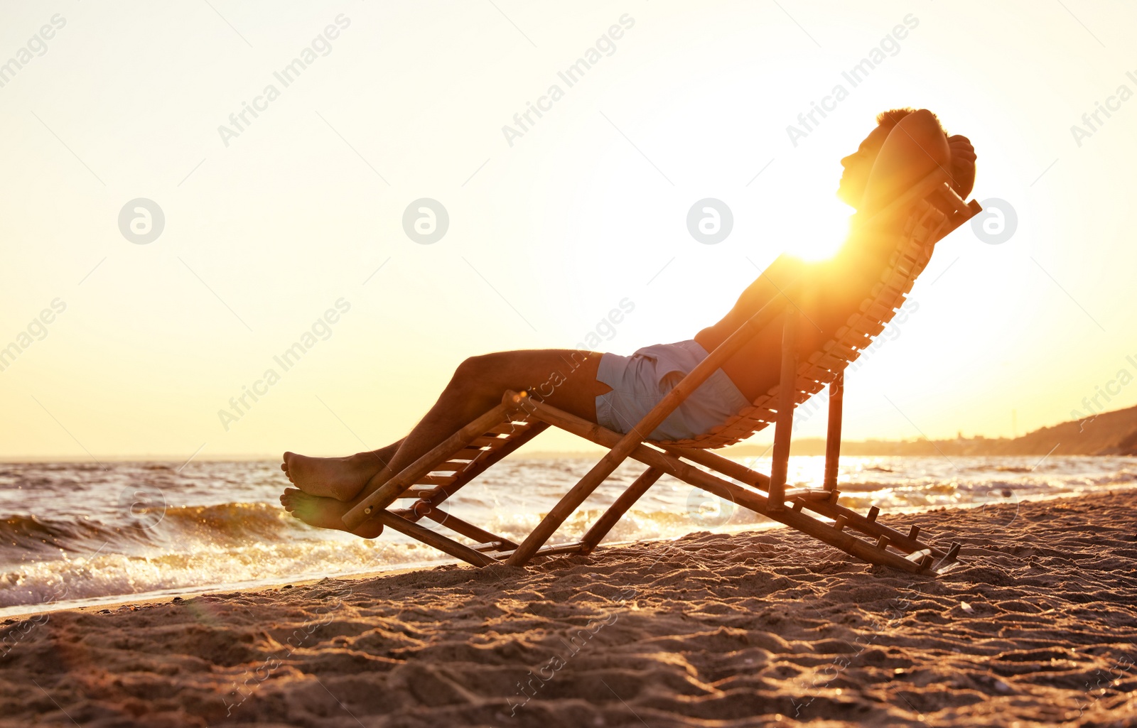 Photo of Young man relaxing in deck chair on beach near sea