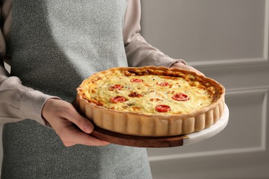 Photo of Woman with delicious homemade cheese quiche indoors, closeup