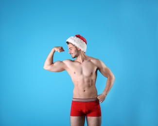 Photo of Shirtless young Santa Claus with sexy body on color background