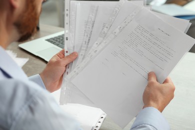 Businessman working with documents at wooden table in office, closeup