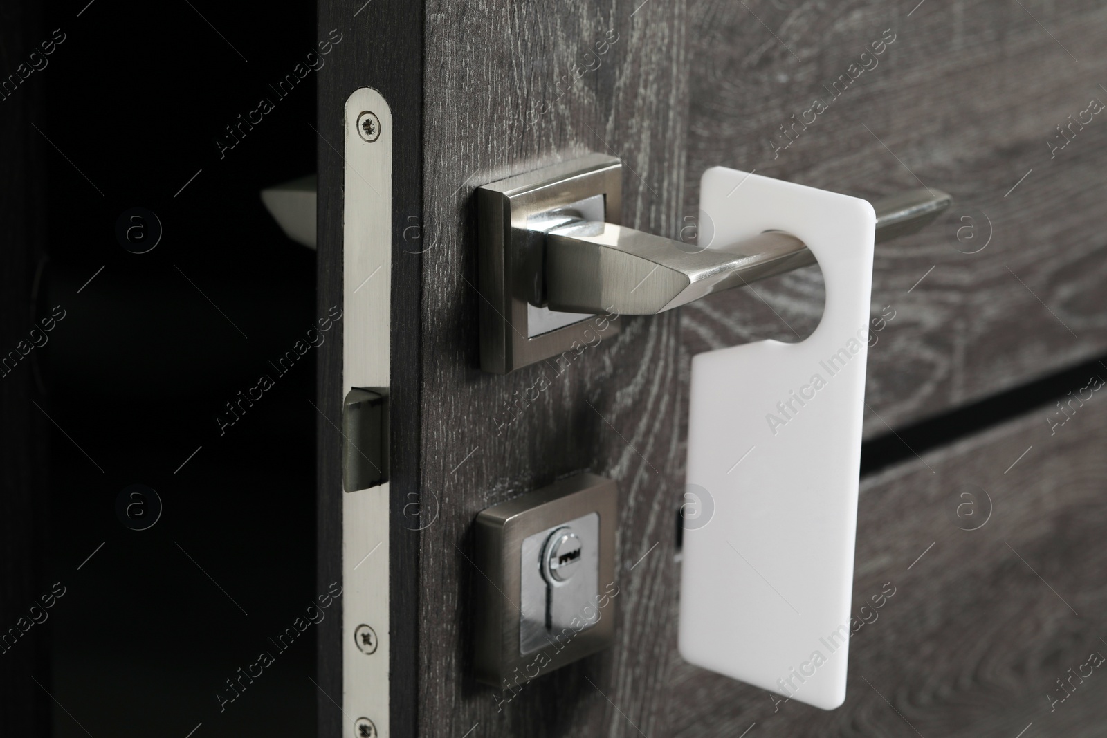 Photo of Wooden door with blank hanger on metal handle, closeup