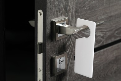 Wooden door with blank hanger on metal handle, closeup