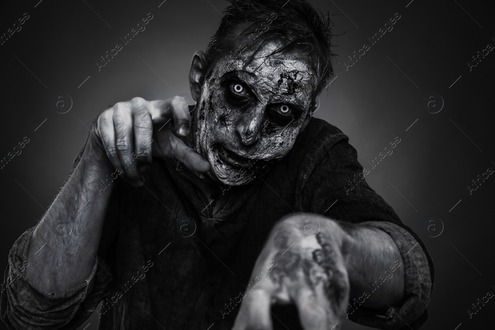 Photo of Scary zombie on dark background, black and white effect. Halloween monster