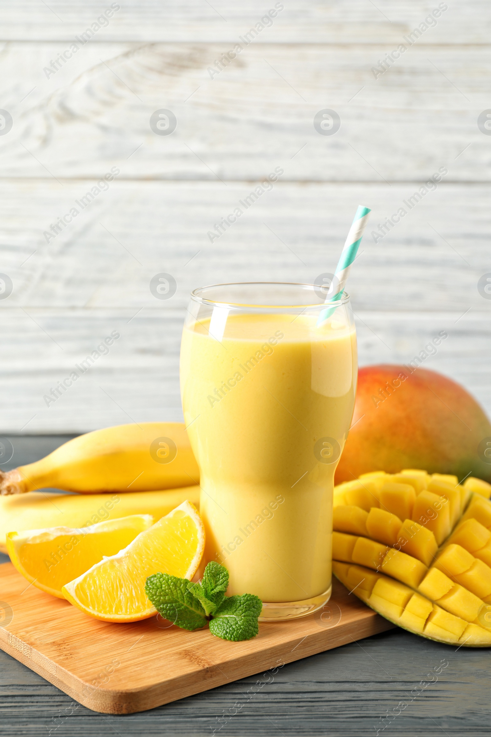 Photo of Tasty tropical drink with mango and fresh fruits on wooden table. Space for text