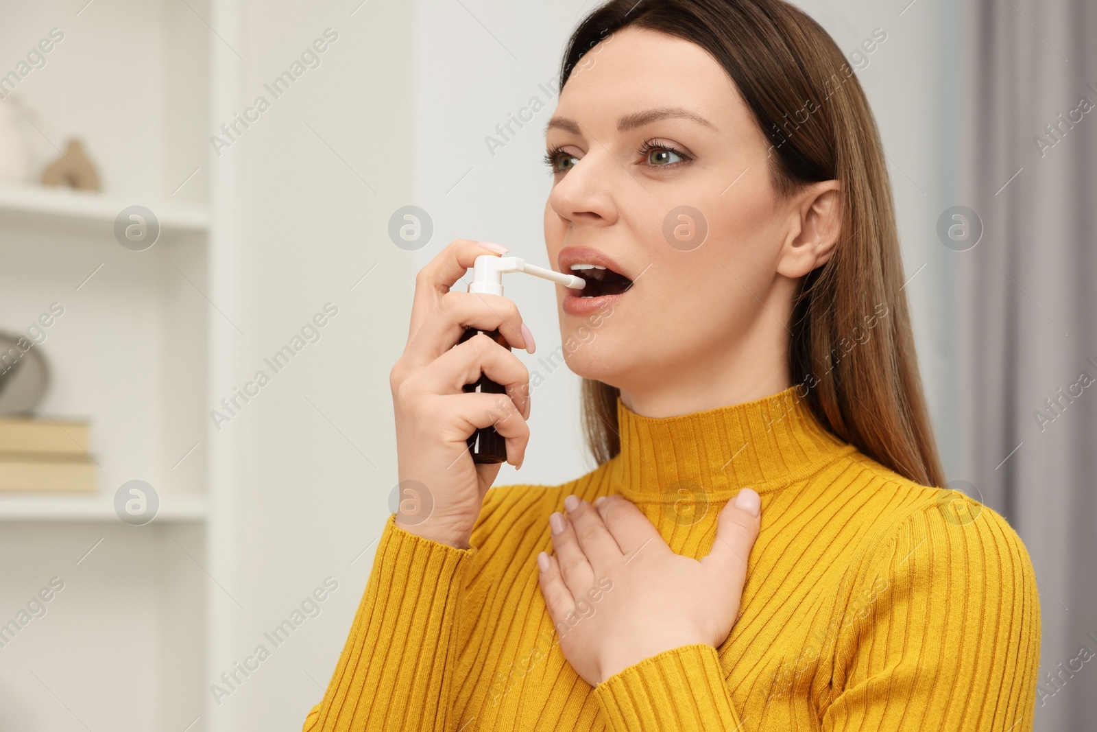 Photo of Adult woman using throat spray at home, space for text