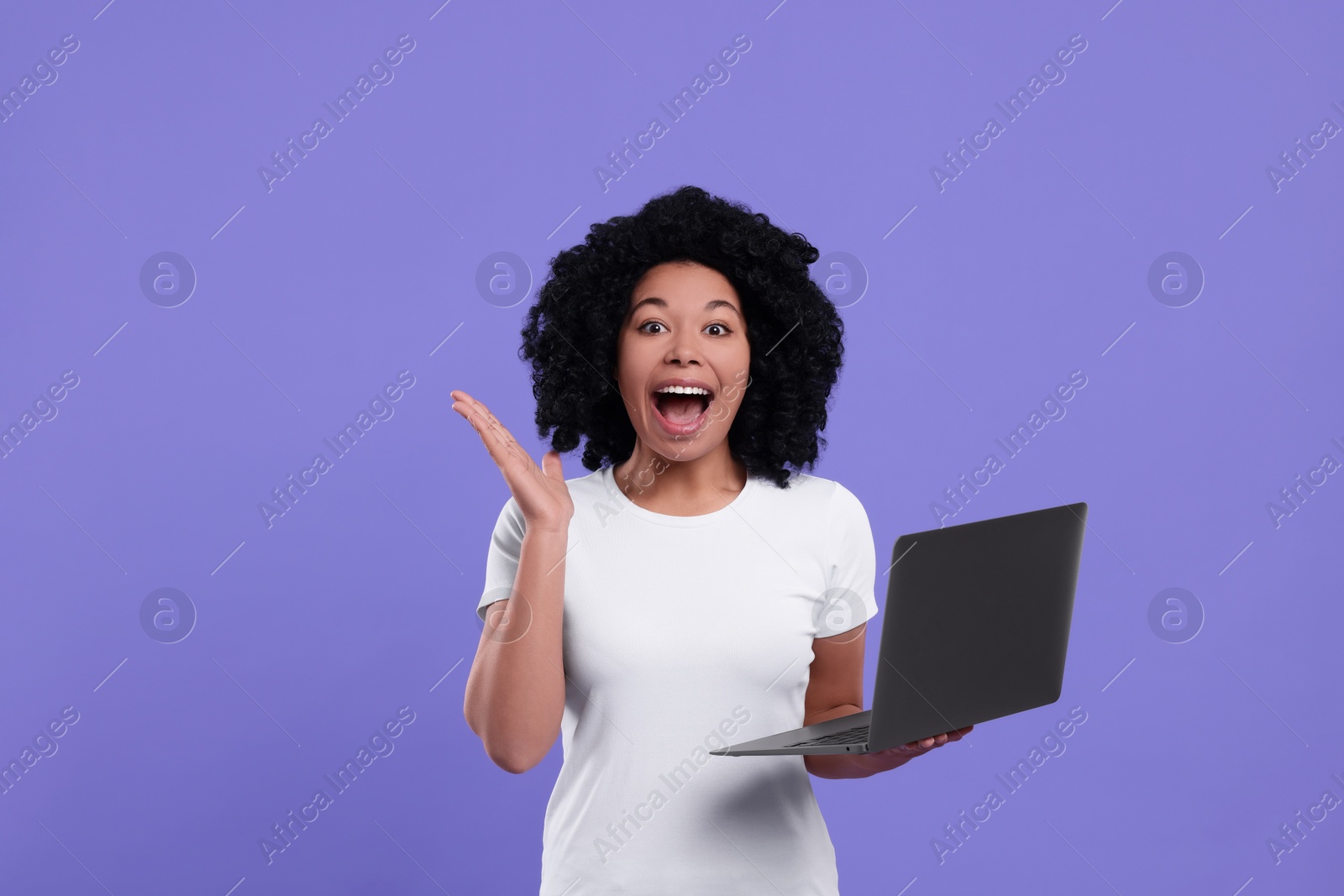 Photo of Emotional young woman with laptop on purple background