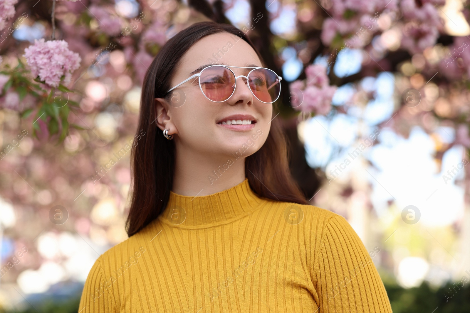 Photo of Beautiful woman in sunglasses near blossoming tree on spring day