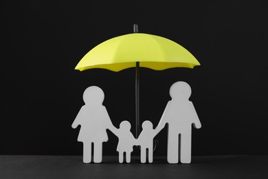 Photo of Small umbrella and family figure on black background