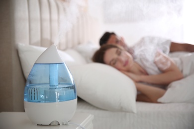 Couple sleeping in bedroom with modern air humidifier