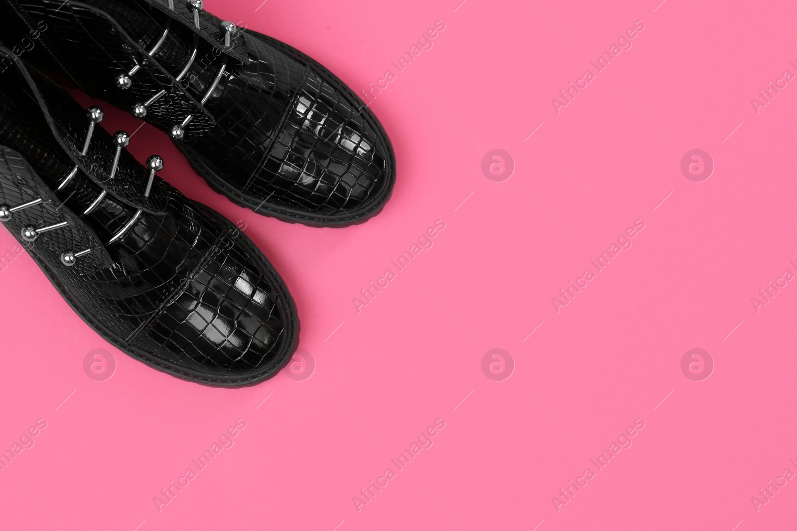 Photo of Pair of stylish ankle boots on pink background, top view. Space for text