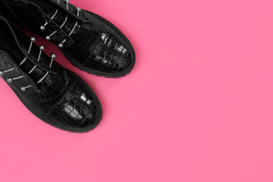 Pair of stylish ankle boots on pink background, top view. Space for text