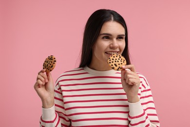 Photo of Young woman with chocolate chip cookies on pink background