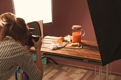 Photo of Woman taking picture of oranges and jug with juice on table. Food photography
