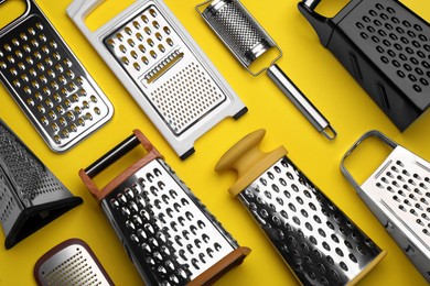 Photo of Different modern graters on yellow background, flat lay