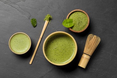 Fresh matcha tea, bamboo whisk, spoon and green powder on black table, flat lay