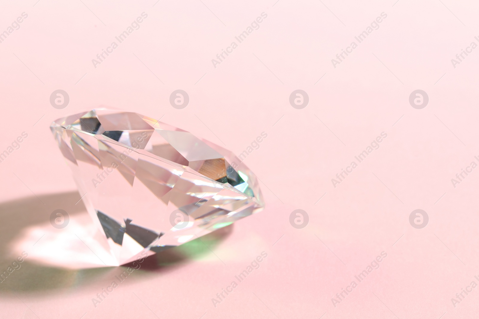 Photo of Beautiful dazzling diamond on pink background. Space for text