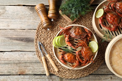 Photo of Delicious boiled crabs with lime on wooden table, flat lay. Space for text