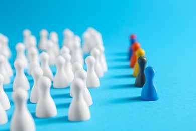 Photo of Colorful pawns on light blue background. Social inclusion concept