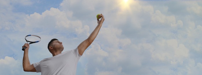 Image of Man serving ball while playing tennis outdoors, low angle view. Banner design with space for text