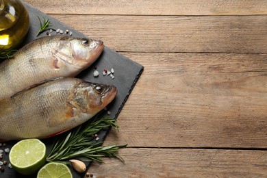 Photo of Fresh raw perches and ingredients on wooden table, top view with space for text. River fish