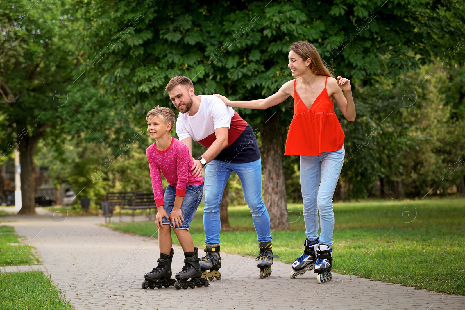 Photo of Young happy family roller skating in summer park