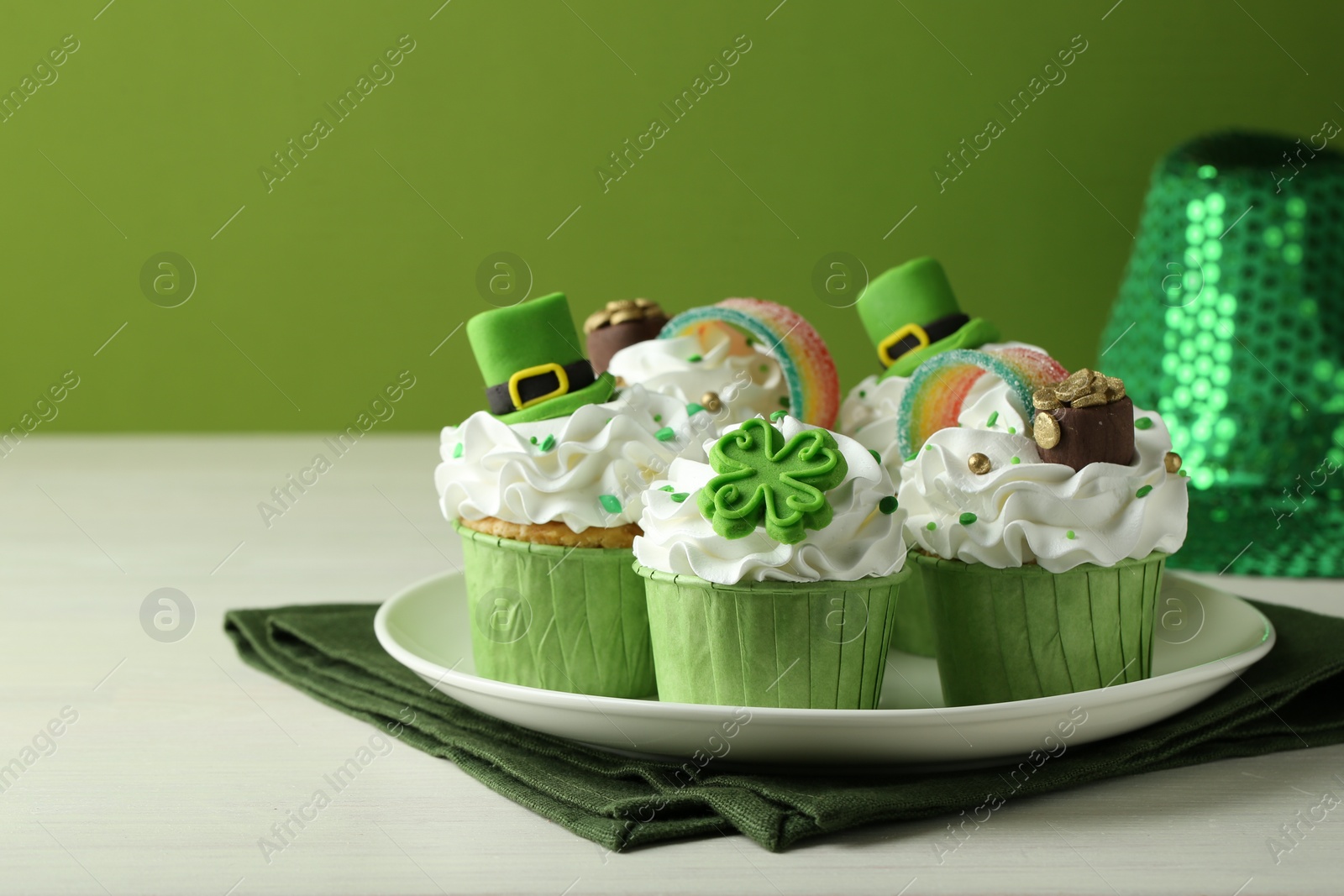 Photo of St. Patrick's day party. Tasty festively decorated cupcakes on white table, closeup. Space for text