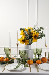 Beautiful autumn table setting with bouquet indoors. Plates, cutlery, glasses and floral decor