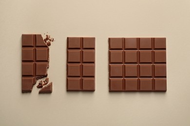 Photo of Delicious broken chocolate bar on beige background, flat lay