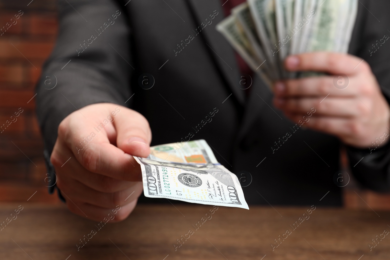 Photo of Man holding money at wooden table, closeup. Currency exchange