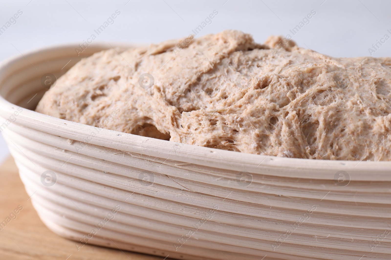 Photo of Fresh sourdough in proofing basket on table, closeup