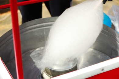 Man making cotton candy with machine outdoors, closeup