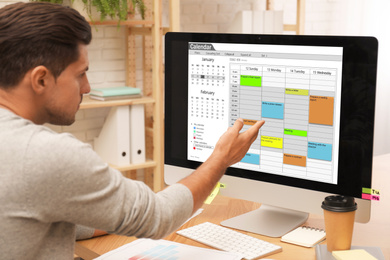 Photo of Handsome man using calendar app on computer in office