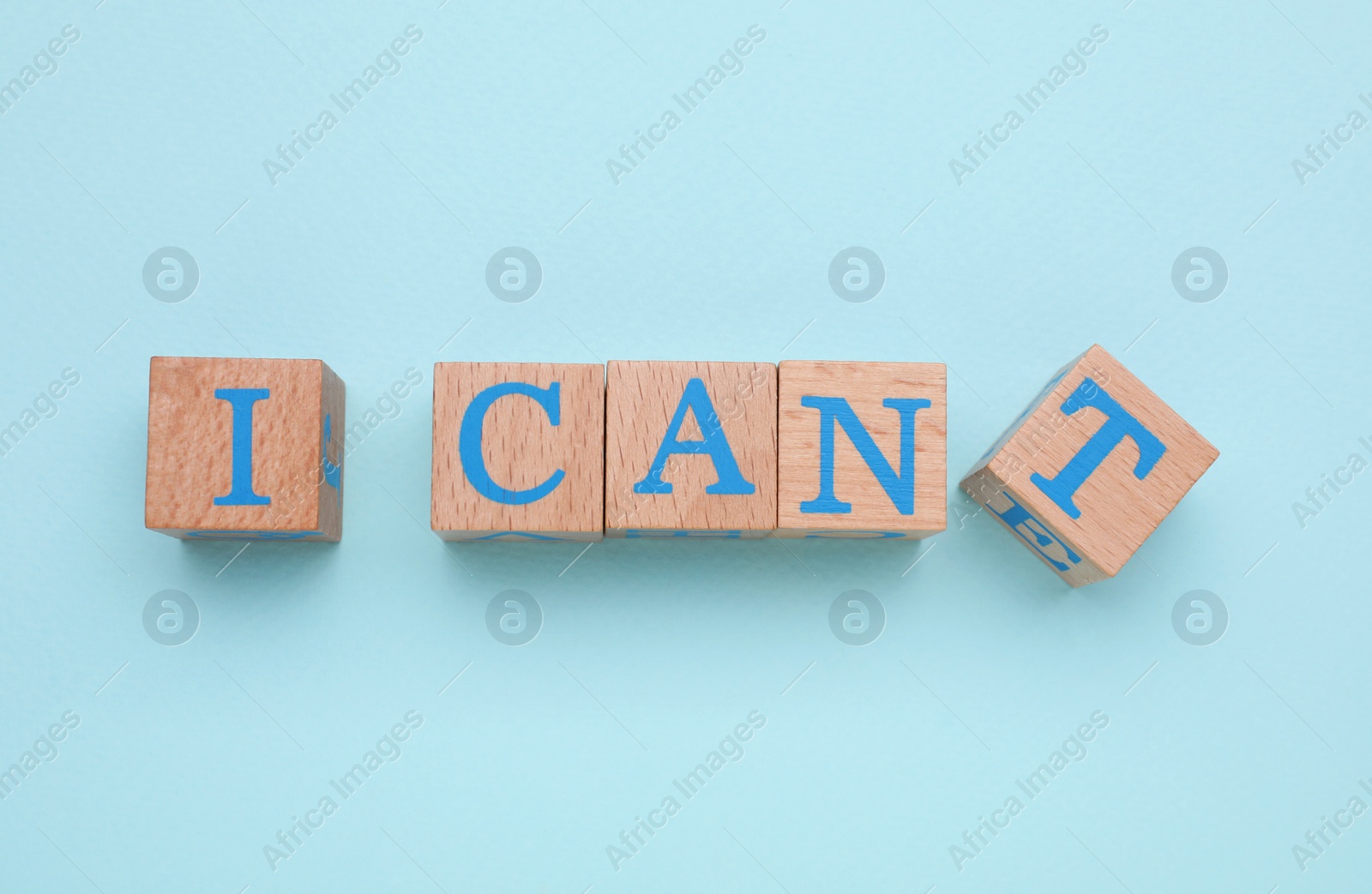 Photo of Motivation concept. Changing phrase from I Can't into I Can by removing wooden cube with letter T on light blue background, flat lay