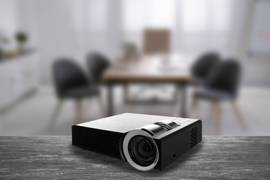 Modern video projector and blurred conference room on background