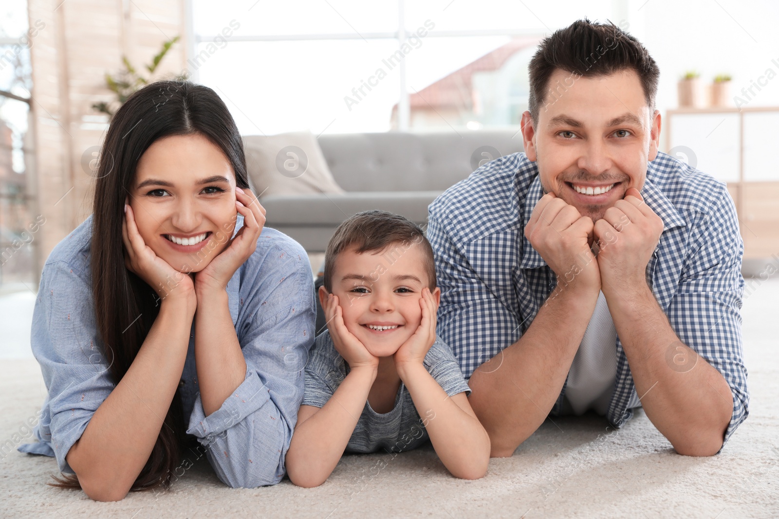 Photo of Happy couple and their son lying on carpet at home. Family time