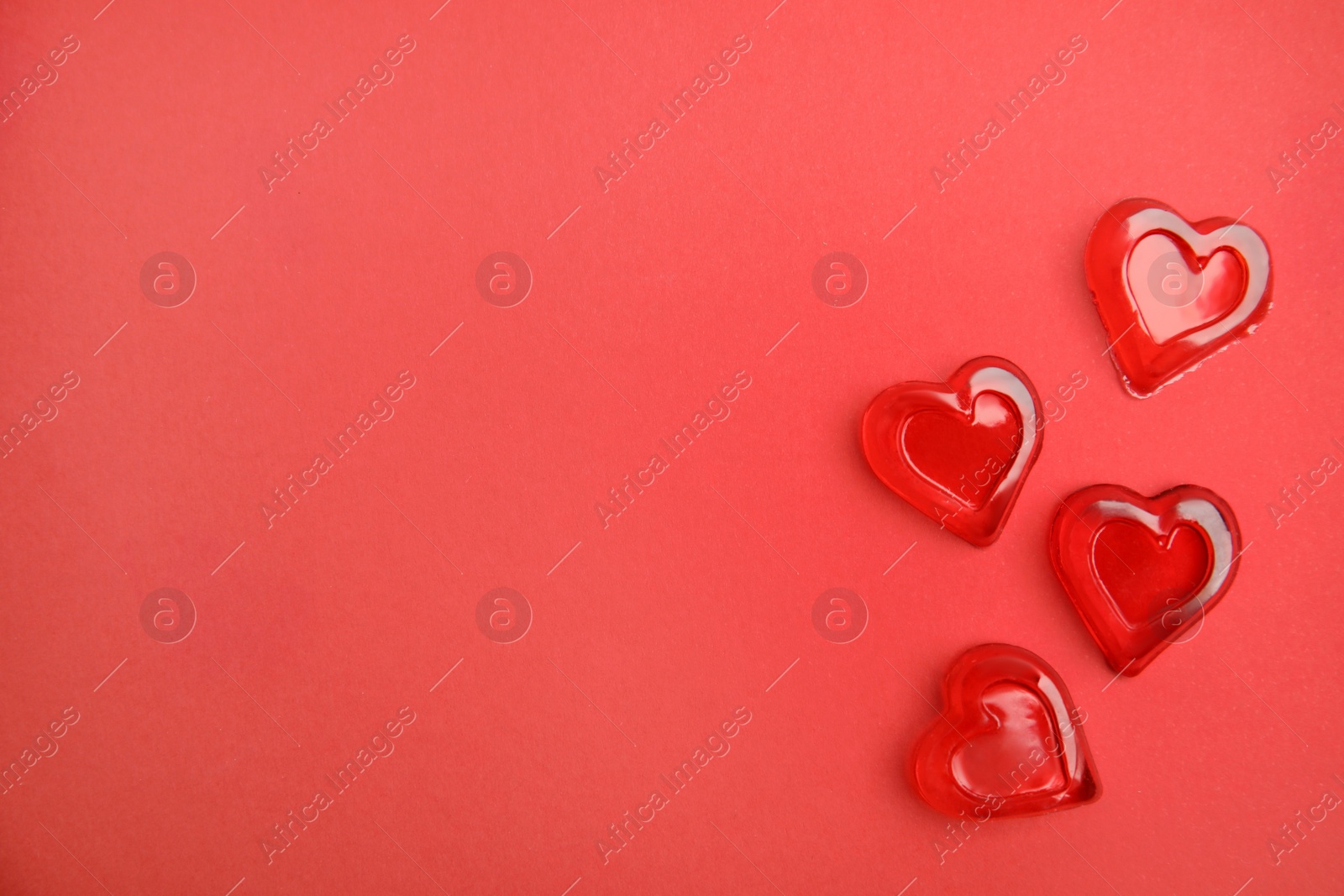 Photo of Sweet heart shaped jelly candies on red background, flat lay. Space for text