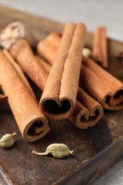 Photo of Cinnamon sticks and cardamon pods on wooden board, closeup