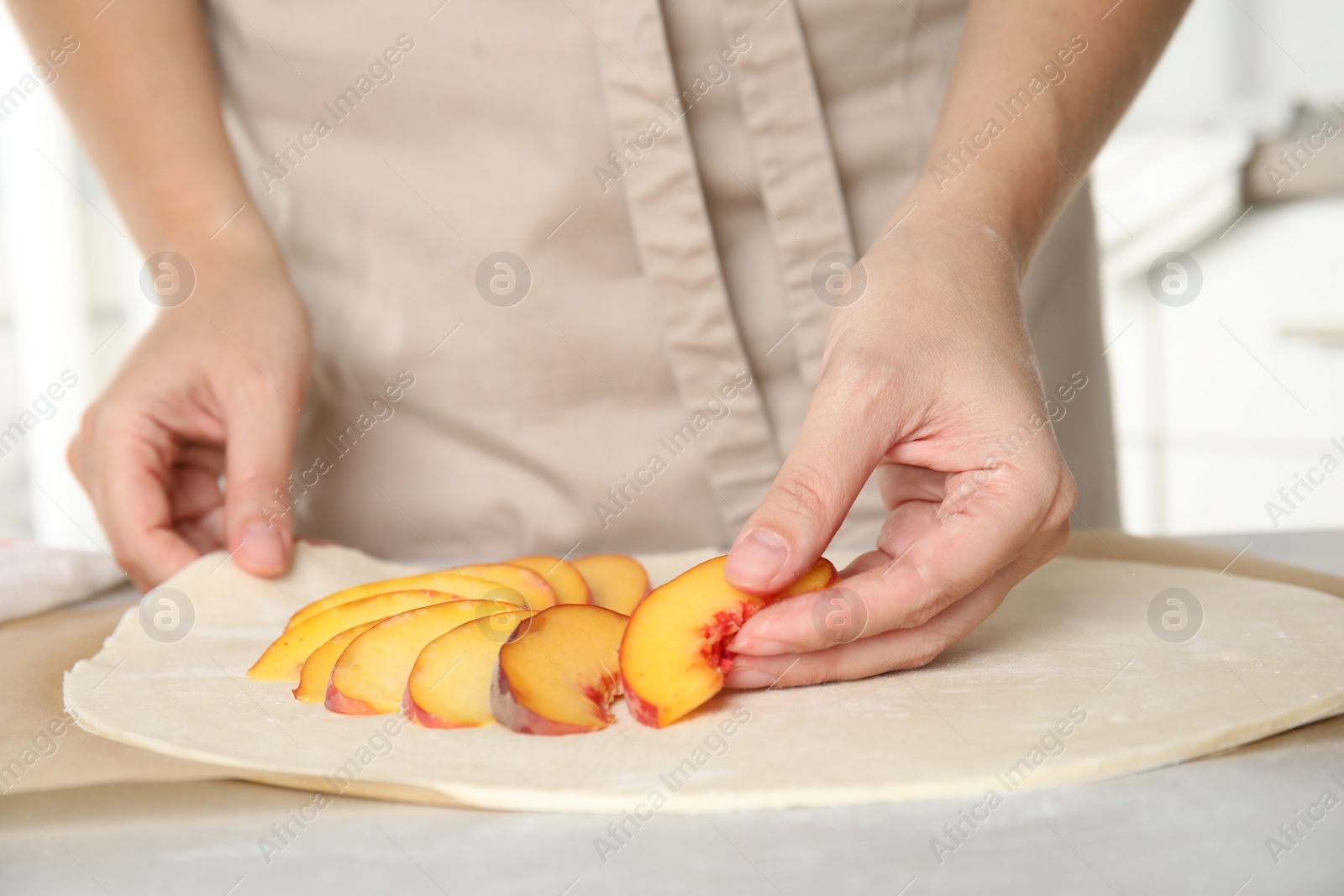 Photo of Woman making peach pie at kitchen table, closeup