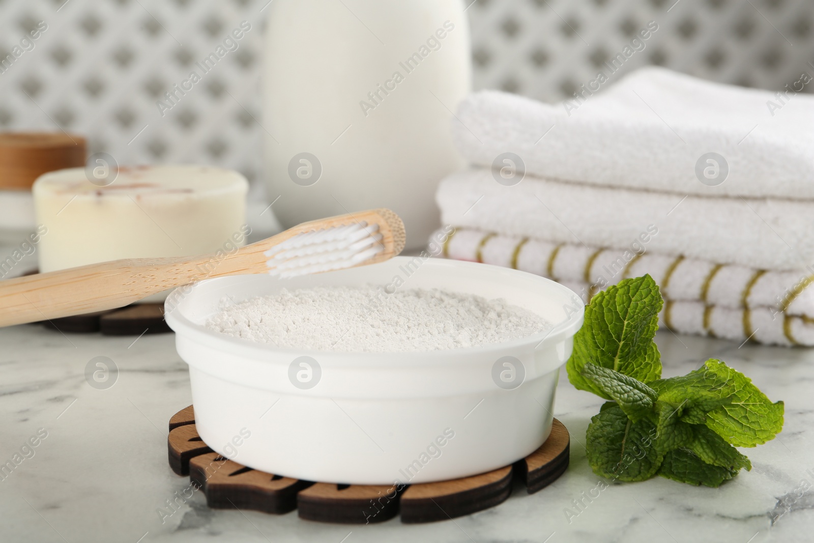 Photo of Tooth powder, brush and mint on white marble table, closeup
