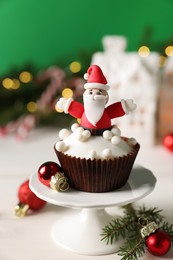 Tasty Christmas cupcake with Santa Claus figure on white table