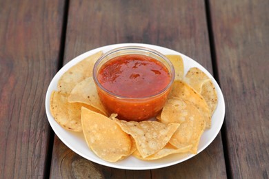 Tasty salsa sauce and tortilla chips on wooden table, closeup