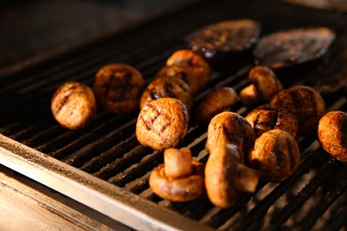 Photo of Cooking delicious mushrooms on grilling grate in oven