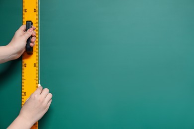 Photo of Woman drawing with chalk and ruler on green board, closeup. Space for text