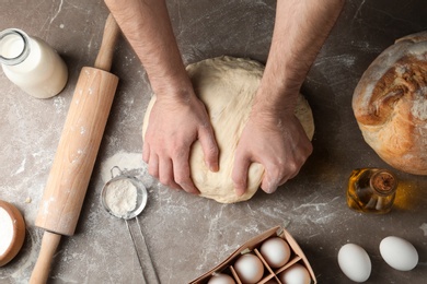 Photo of Male baker preparing bread dough at kitchen table, top view