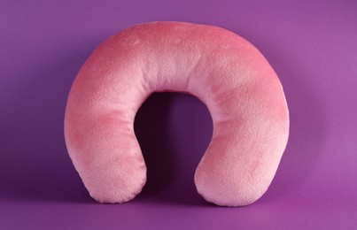 Photo of One pink travel pillow on violet background