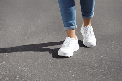 Photo of Woman in stylish sneakers walking outdoors, focus on legs