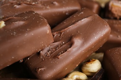 Delicious chocolate candy bars with nuts as background, closeup