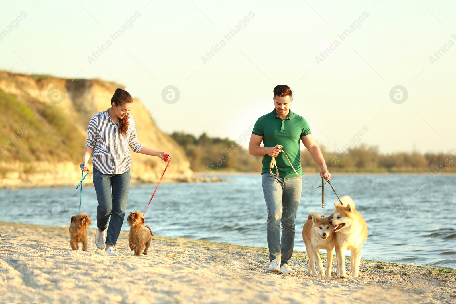 Photo of Young couple walking their adorable dogs near river