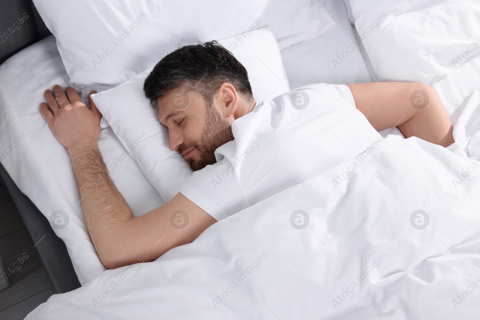 Photo of Handsome man sleeping in soft bed, top view